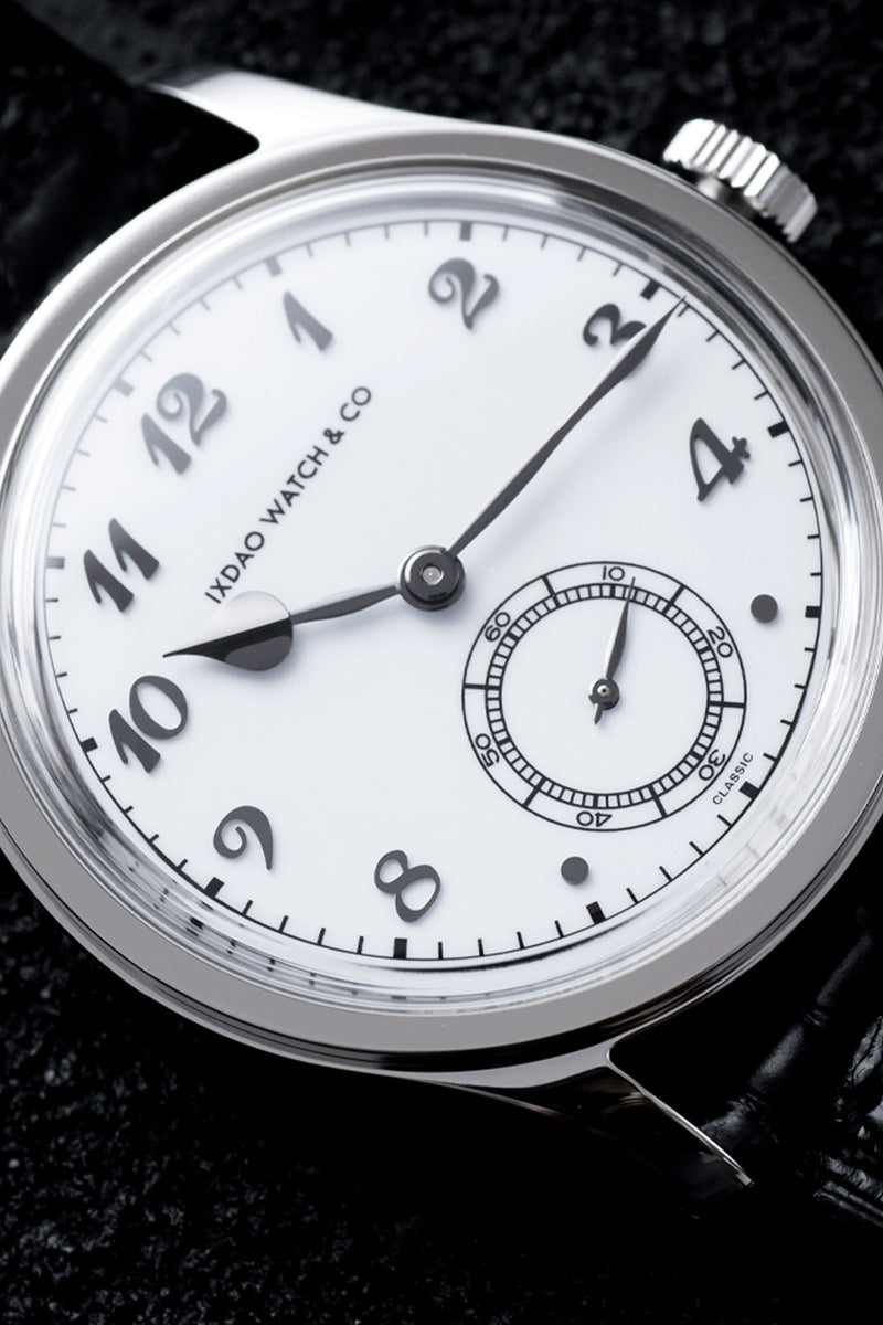 A close-up of a silver-tone wristwatch with a white dial, black Arabic numerals, and a small seconds subdial. The brand name 'INDIO WATCH & CO' is printed on the dial.