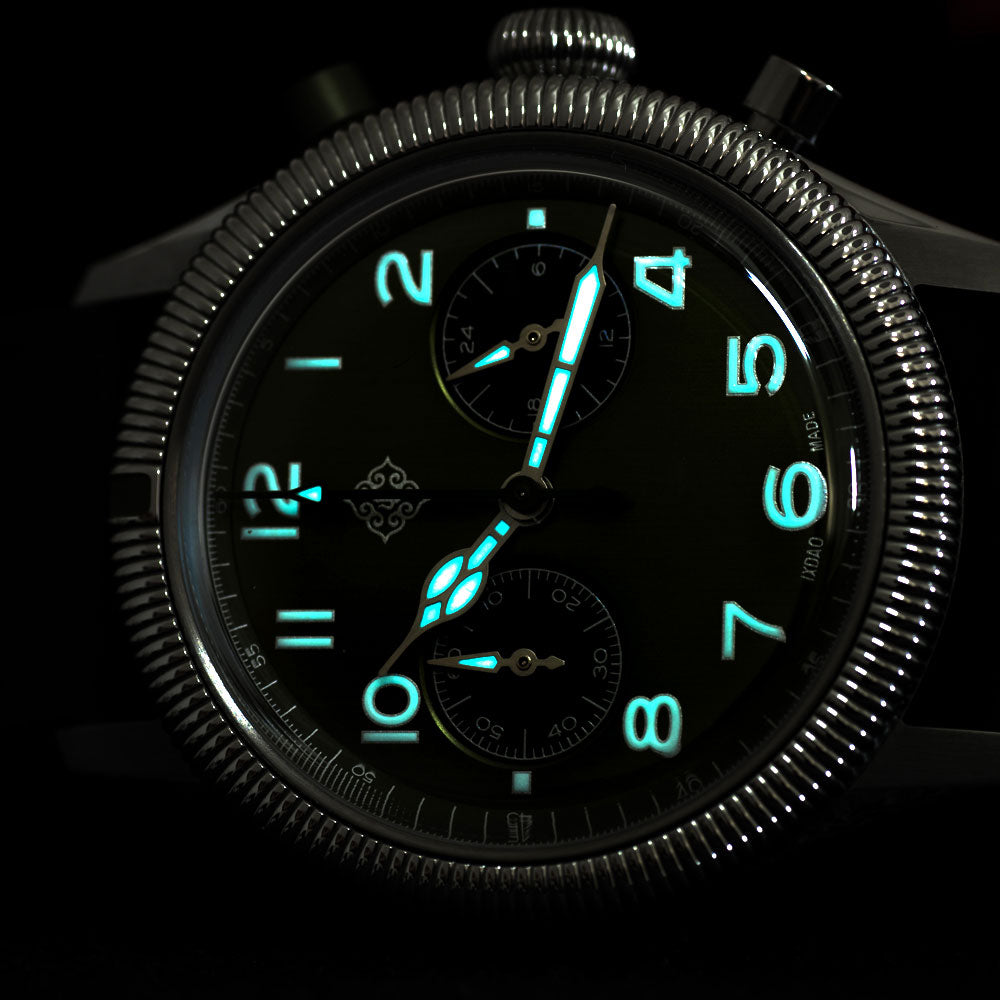 Close-up of a wristwatch with a black dial, luminous green hour markers and hands, and a textured silver-tone case against a black background.