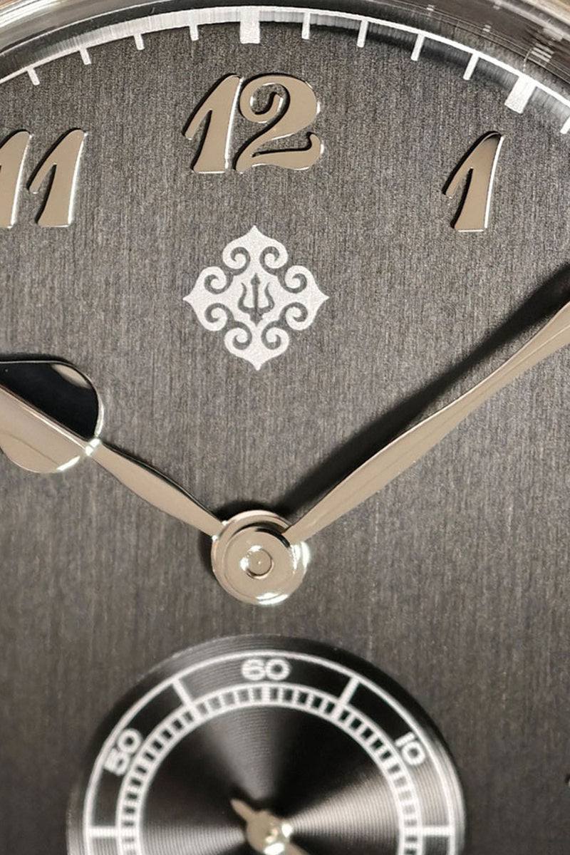 Close-up of a dark gray textured dial clock face with silver-tone numerals, hands, and a small circular subdial at the bottom.