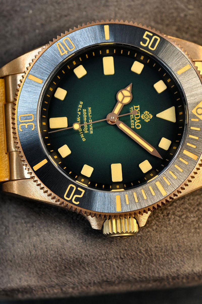 A close-up of a DNGA automatic watch with a gold-tone case, a blue and black rotating bezel, and a dark green dial with gold-tone indices.