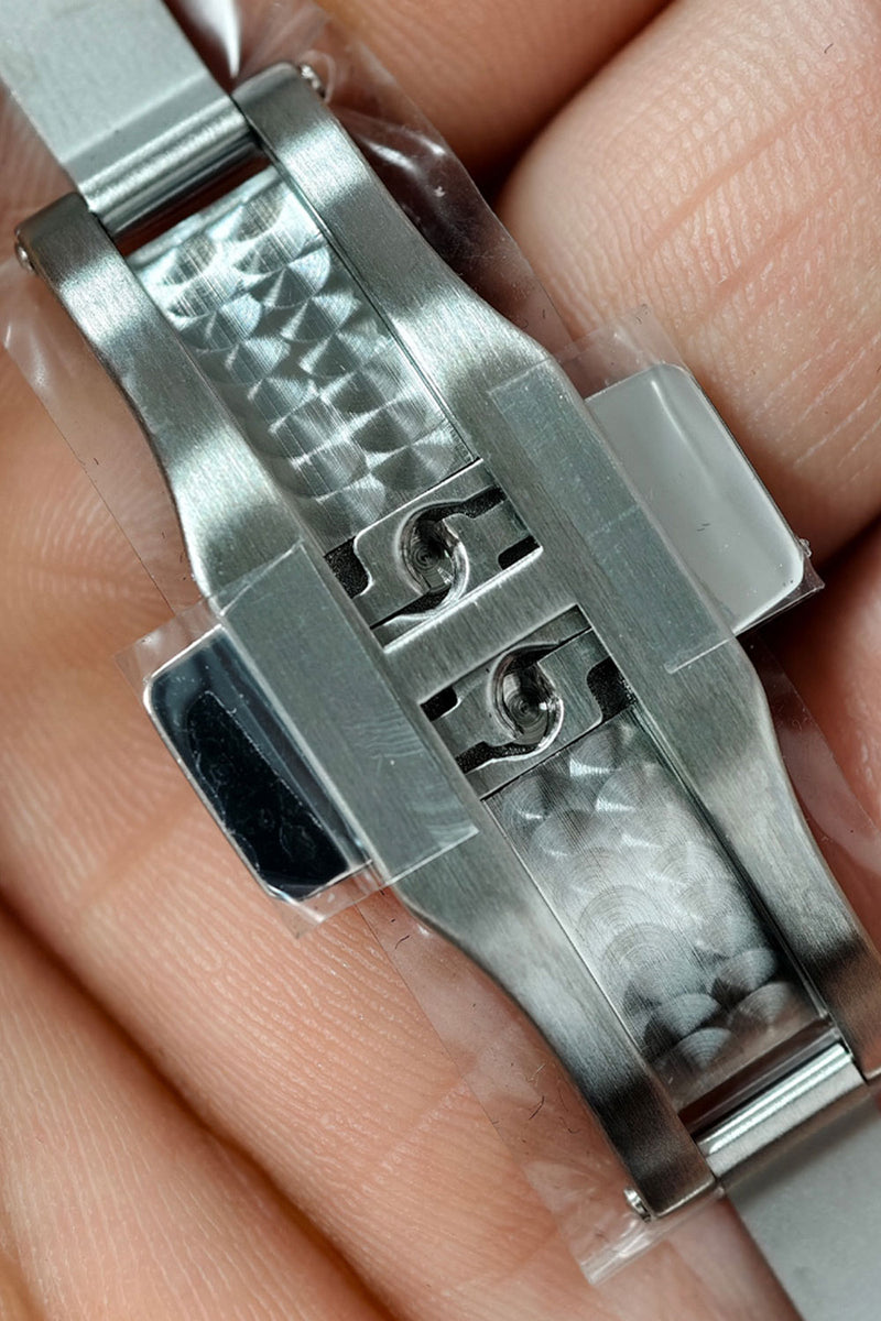 Close-up of a stainless steel watch band clasp being held between fingers, showing the textured lugs and metal construction.