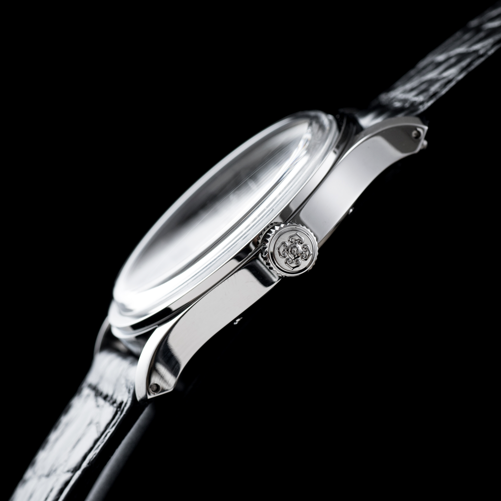 Close-up side view of a silver-toned wristwatch with a textured dark strap, shown against a solid black background.