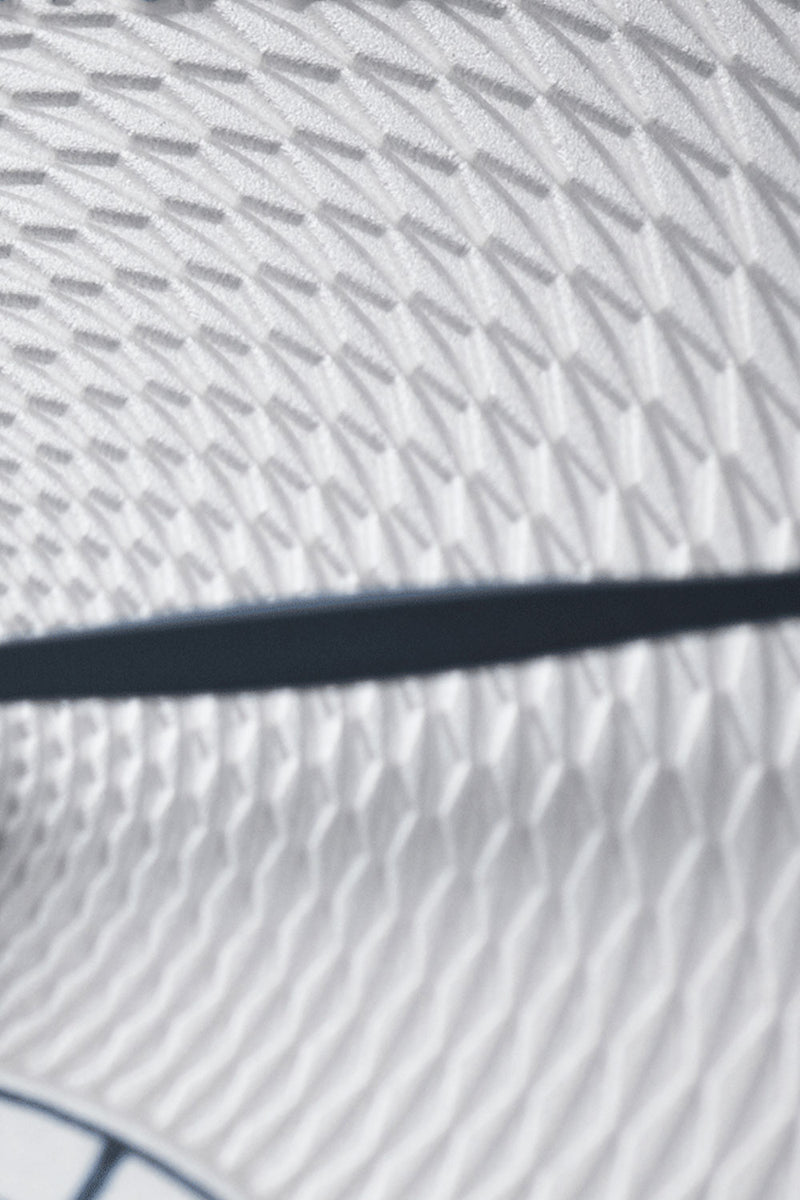 Close-up of a white textured surface with a repeating geometric pattern and a dark horizontal stripe across the center.