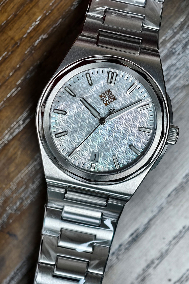 A vintage-style stainless steel wristwatch with a textured silver dial and matching metal link bracelet, resting on a rustic wooden surface.