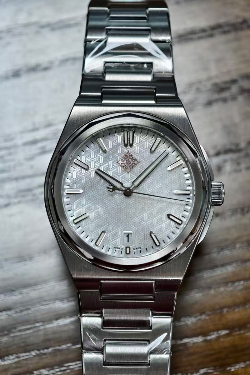 A stainless steel wristwatch with a textured silver dial and matching metal link bracelet, resting on a wooden surface.